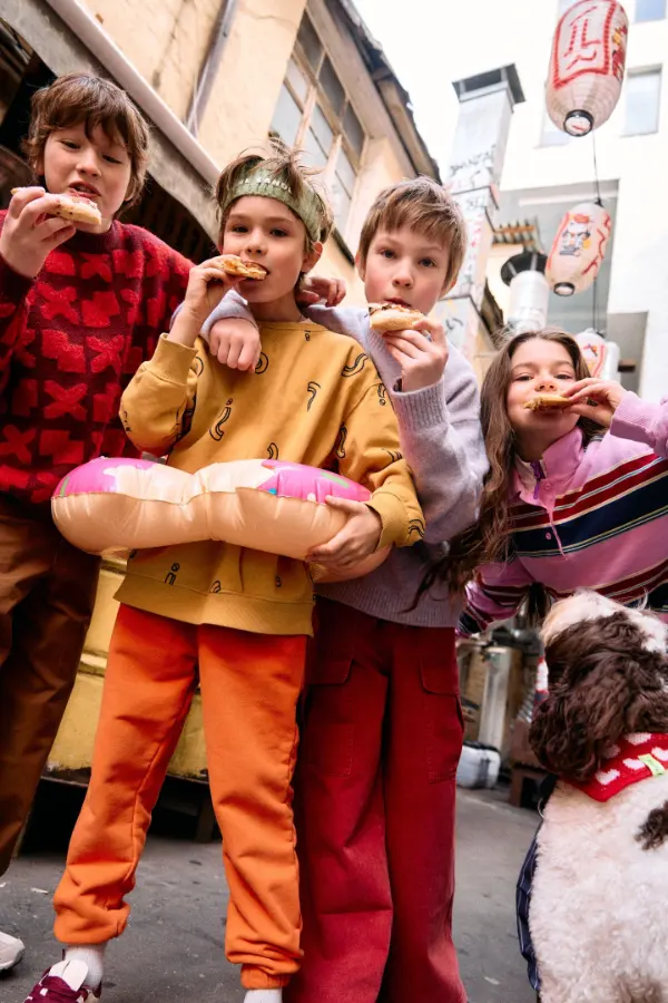 Kids in orange and red outfits on a city street